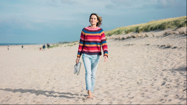 mujer madura caminando sobre la arena de la playa