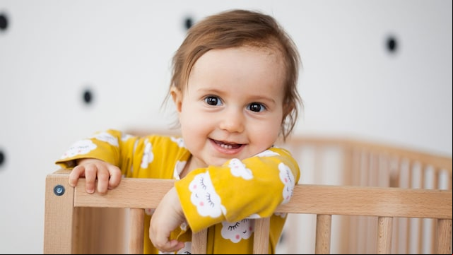 Niña pequeña de pie en la cuna