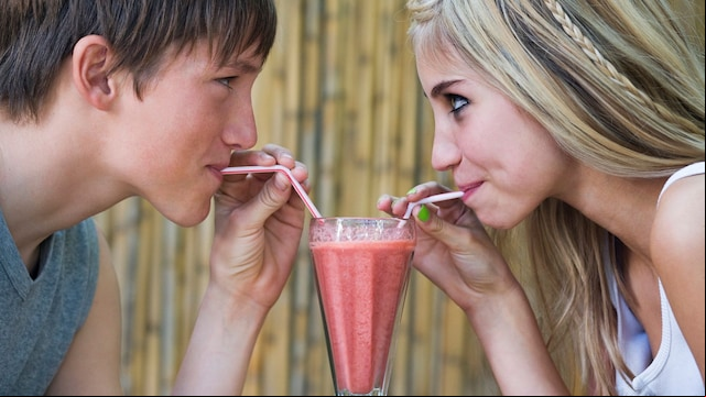 Adolescentes beben un batido del mismo vaso con pajitas