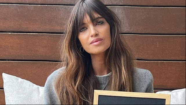 Sara Carbonero sujetando un carte de 'Cobarde' sentada en un sillón