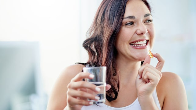 Mujer joven tomándose un suplemento de vitaminas