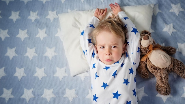 ni o maldormido en la cama con osito de peluche