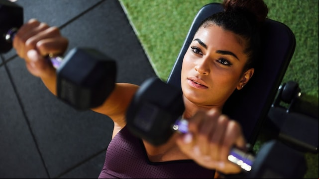 Mujer entrenando con pesas en banco de gimnasio