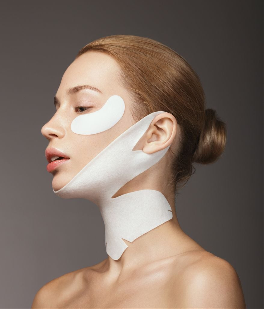 Mujer con mascarillas de piel en cuello, mandíbula y ojos
