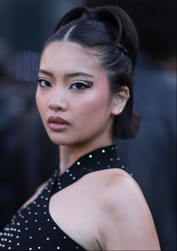 Mujer con pelo corto y semirrecogido, maquillaje de ojos arty y vestido negro con brillantes