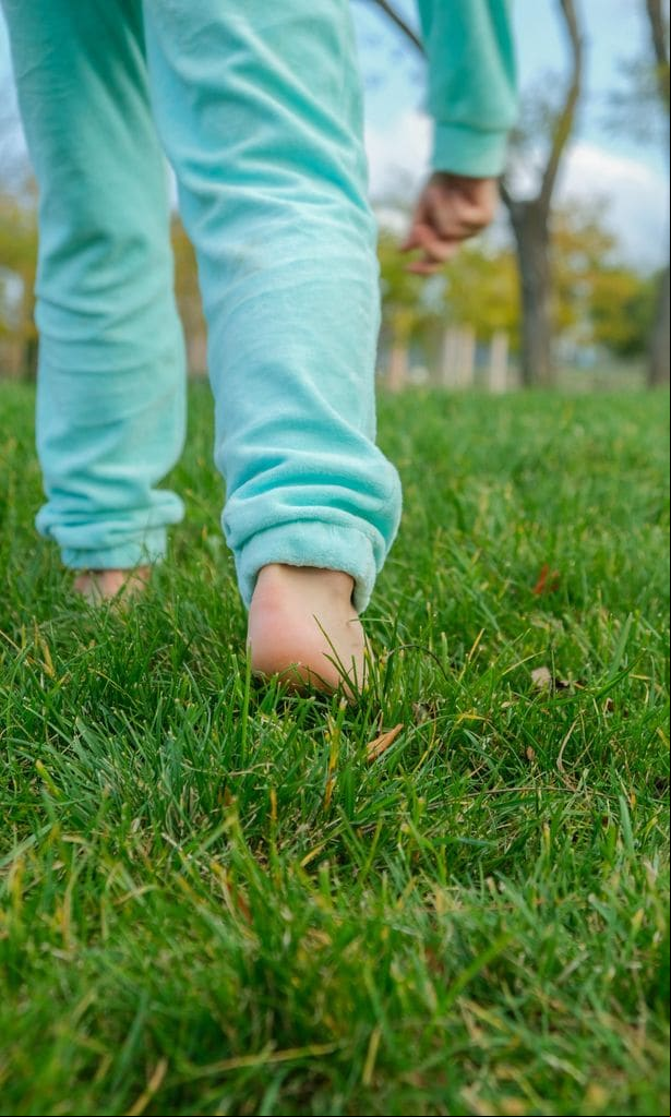 Niño caminando descalzo sobre el césped