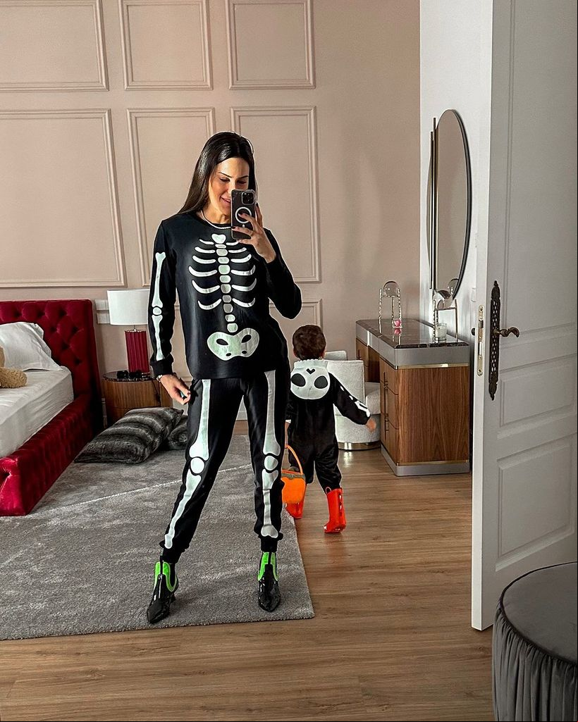 Plano entero de Carla Barber disfrazada de esqueleto con su hijo en Halloween 2024