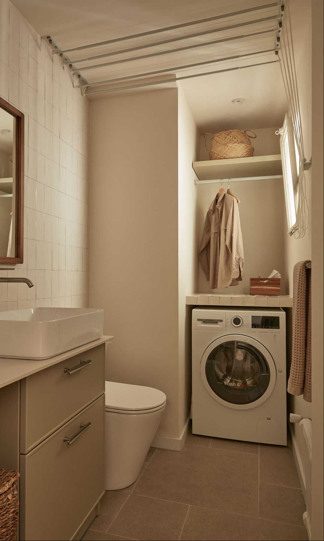 Lavadero en el baño con lavadora, barra para la ropa, estanterías y cestos