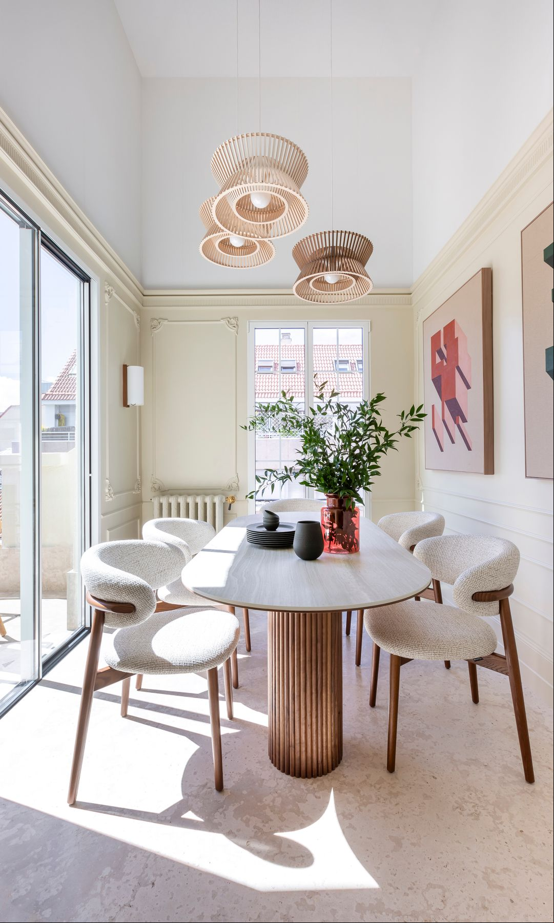 Comedor con salida a la terraza, sillas tapizadas, mesa de madera, lámparas de techo y cuadros